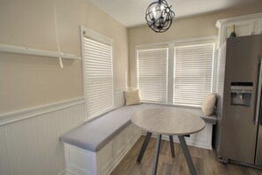 A kitchen with a built-in bench seating area, a refrigerator, and a pendant light fixture. - Indy Gameday House - Downtown - 10 Walk to Lucas Oil Stadium (Indianapolis)