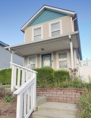 A two-story house with a front porch, a brick foundation, and a clear blue sky. - Indy Gameday House - Downtown - 10 Walk to Lucas Oil Stadium (Indianapolis)