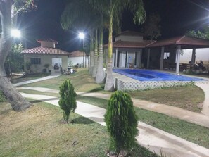A residential area with a swimming pool, pathways, and a covered patio area.