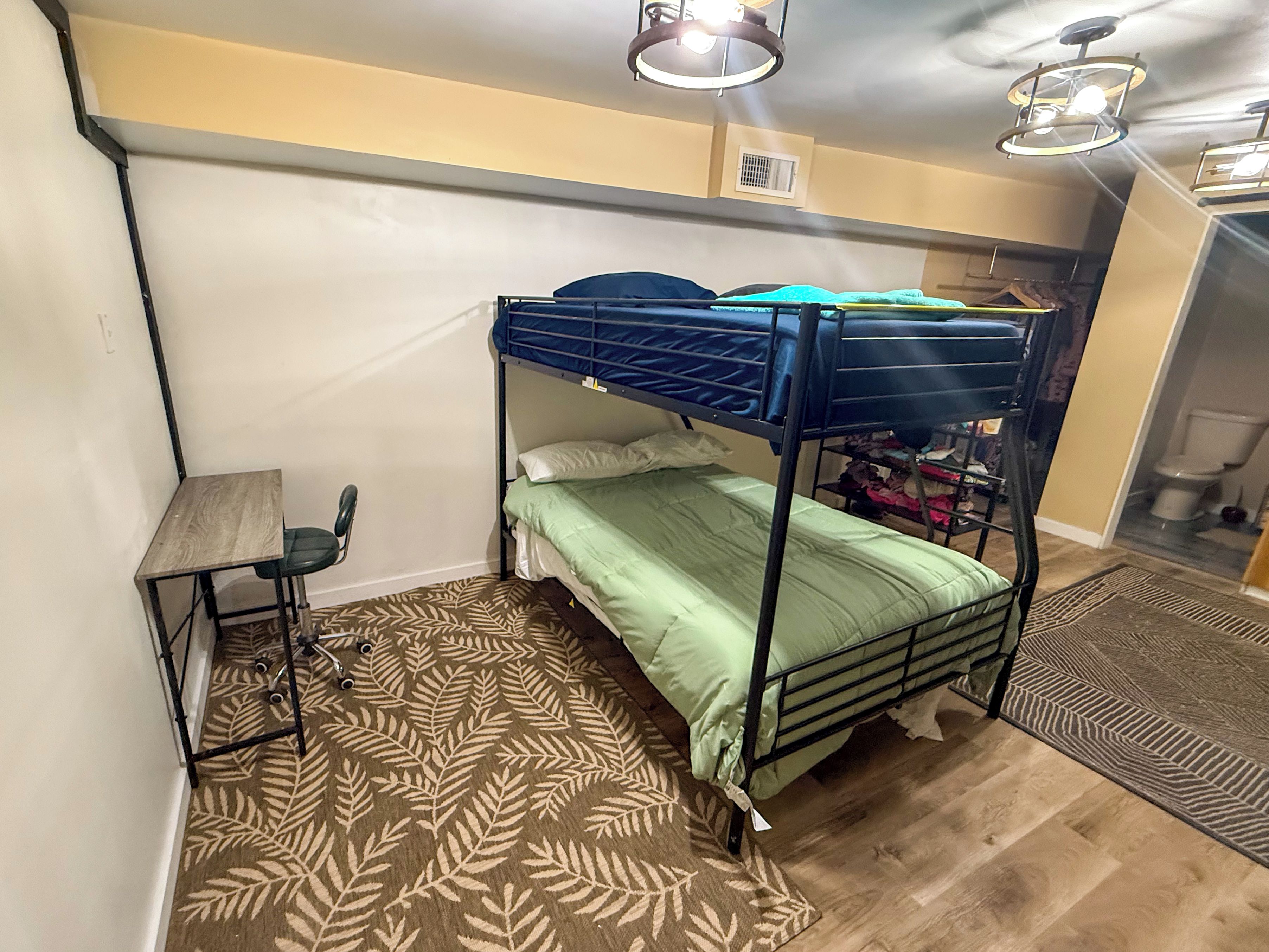 A bunk bed room with a desk and a patterned rug.