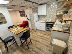 A compact kitchen with a dining area, a built-in oven, and a small trash bin. - The Flight Crew Quarters (College Park)