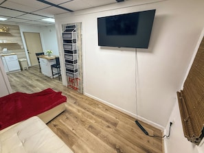 A room with a bed, a desk with a chair, a TV mounted on the wall, and a window with curtains. - The Flight Crew Quarters (College Park)