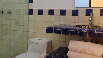 Een badkamer met toilet, wastafel en spiegel.