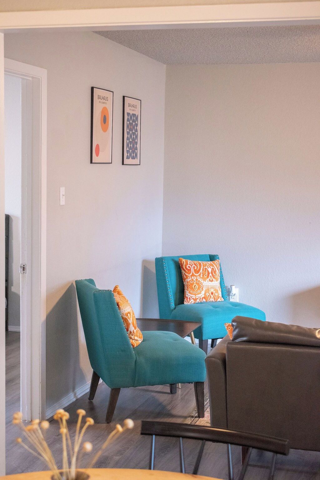 A living room with teal and brown furniture, a coffee table, and two framed artworks on the wall.