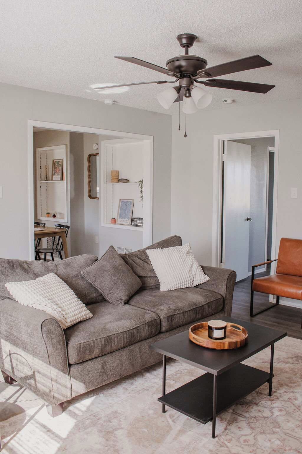 A modern living room with a grey sofa, a black coffee table, and a ceiling fan.