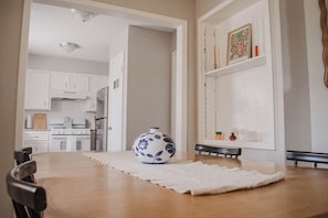 Een eetruimte met een tafel, stoelen, een decoratieve vaas en een lijst met een afbeelding aan de muur.