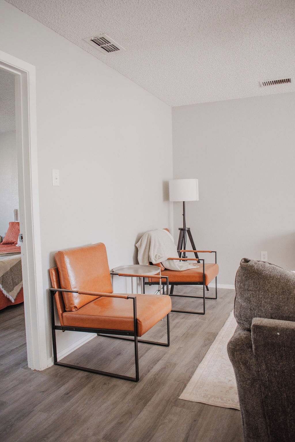 A modern living room with two leather armchairs, a small table, and a floor lamp.
