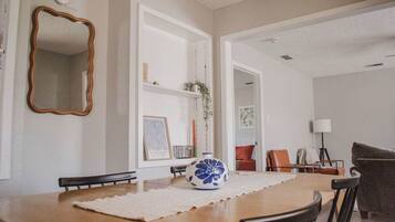 A dining area with a wooden table, chairs, a decorative vase, and a mirror on the wall.
