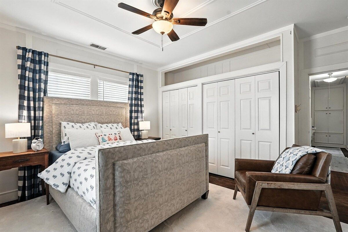 A bedroom with a bed, a chair, a desk, a wardrobe, and a ceiling fan.