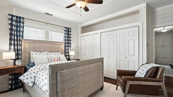Une chambre à coucher comprenant un lit, une chaise, un bureau, une armoire et un ventilateur de plafond.