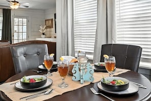 Mesa de comedor preparada con platos, vasos y un centro de mesa decorativo.