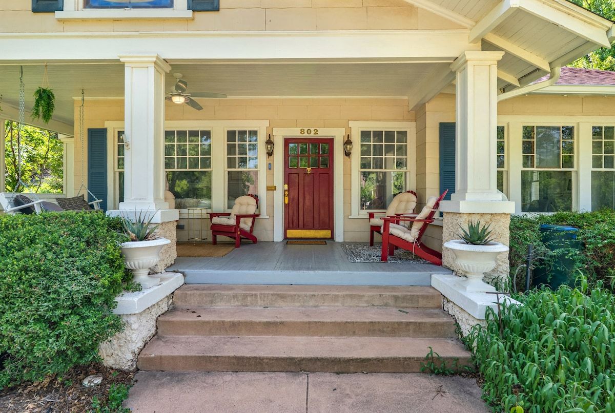 A house with a front porch, a red door, and steps leading to the entrance.