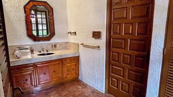 Une salle de bain avec un meuble-lavabo en bois, un évier, un miroir et une porte.