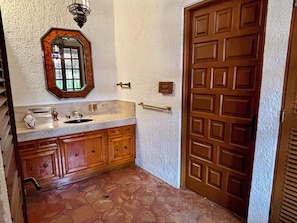 Une salle de bain avec un meuble-lavabo en bois, un évier, un miroir et une porte.