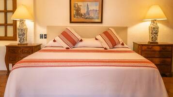Une chambre d’hôtel avec un lit, deux tables de chevet, deux lampes et un tableau encadré au mur.