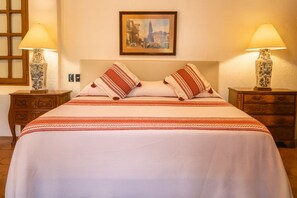 Une chambre d’hôtel avec un lit, deux tables de chevet, deux lampes et un tableau encadré au mur.