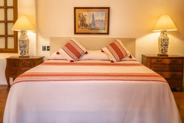 Habitación de hotel con cama, dos mesitas de noche, dos lámparas y un cuadro en la pared.
