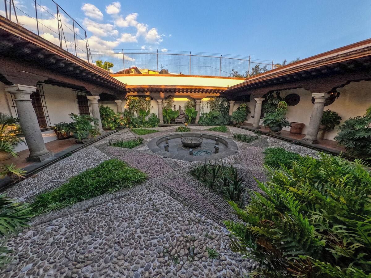 A courtyard with a central fountain, surrounded by stone pathways and greenery.