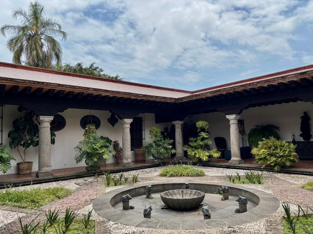 A courtyard with a central fountain, surrounded by columns and potted plants.