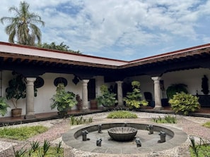 Un patio central con una fuente, rodeado de columnas y plantas en macetas.