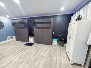 Huoneessa on harmaa lattia, valkoinen vaatekaappi, sininen seinä ja pieni ruukkukasvi.
