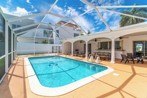 A covered outdoor swimming pool with a patio area, lounge chairs, and a dining table. - Bayfront Villa 4 BR with Heated Pool 10 min walk to Beach (Hollywood)