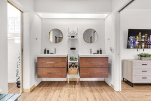 A modern bathroom with two sinks, wooden cabinets, and a central shelf with baskets. - Bayfront Villa 4 BR with Heated Pool 10 min walk to Beach (Hollywood)