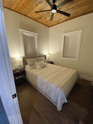 A bedroom with a bed, two bedside lamps, a ceiling fan, and two windows with blinds. - Secluded Hot Springs Cabin with Mountain Views & Fire Pit (Hot Springs)