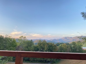 A view from a wooden deck overlooking a forested valley with distant mountains. - Secluded Hot Springs Cabin with Mountain Views & Fire Pit (Hot Springs)