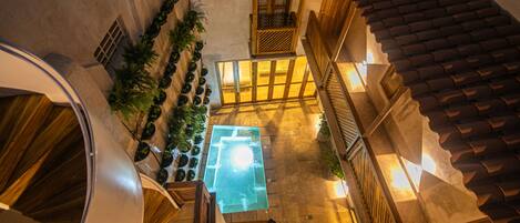 Ein Innenhof mit Pool mit Glasboden, Holzgeländern und Kübelpflanzen.