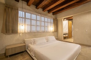 A bedroom with a large bed, wooden beams, a radiator, and a window with curtains. - 5 Bedroom Luxury Villa in Old City (Cartagena de Indias)
