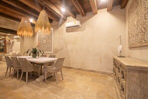 A dining area with a round table, wicker chairs, hanging wicker lamps, and a decorative wall panel. - 5 Bedroom Luxury Villa in Old City (Cartagena de Indias)