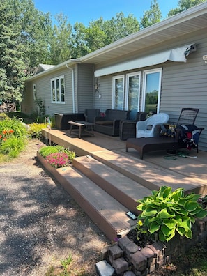 A single-story house with a covered patio area, outdoor furniture, and a garden with various plants.