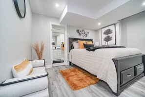 A modern bedroom with a bed, bedside table, and a chair. - LUXE By Marvalous
Luxury 2 bedroom 2 bathroom basement apartment in Brampton. (Brampton)