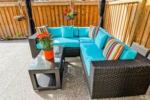 A sectional sofa with multiple cushions, a small glass-top table, and a wicker chair. - LUXE By Marvalous
Luxury 2 bedroom 2 bathroom basement apartment in Brampton. (Brampton)
