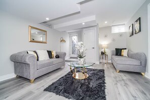 A modern living room with two grey sofas, a glass coffee table, and a black furry rug. - LUXE By Marvalous
Luxury 2 bedroom 2 bathroom basement apartment in Brampton. (Brampton)