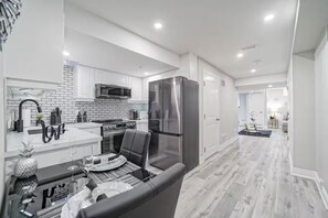A modern kitchen with white cabinets, a stainless steel refrigerator, and a dining area with a table and chairs. - LUXE By Marvalous
Luxury 2 bedroom 2 bathroom basement apartment in Brampton. (Brampton)