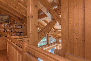 A wooden interior with a sloped ceiling, bookshelves, and a view through a window. - Chalet Nejma - Welkeys (Megève)