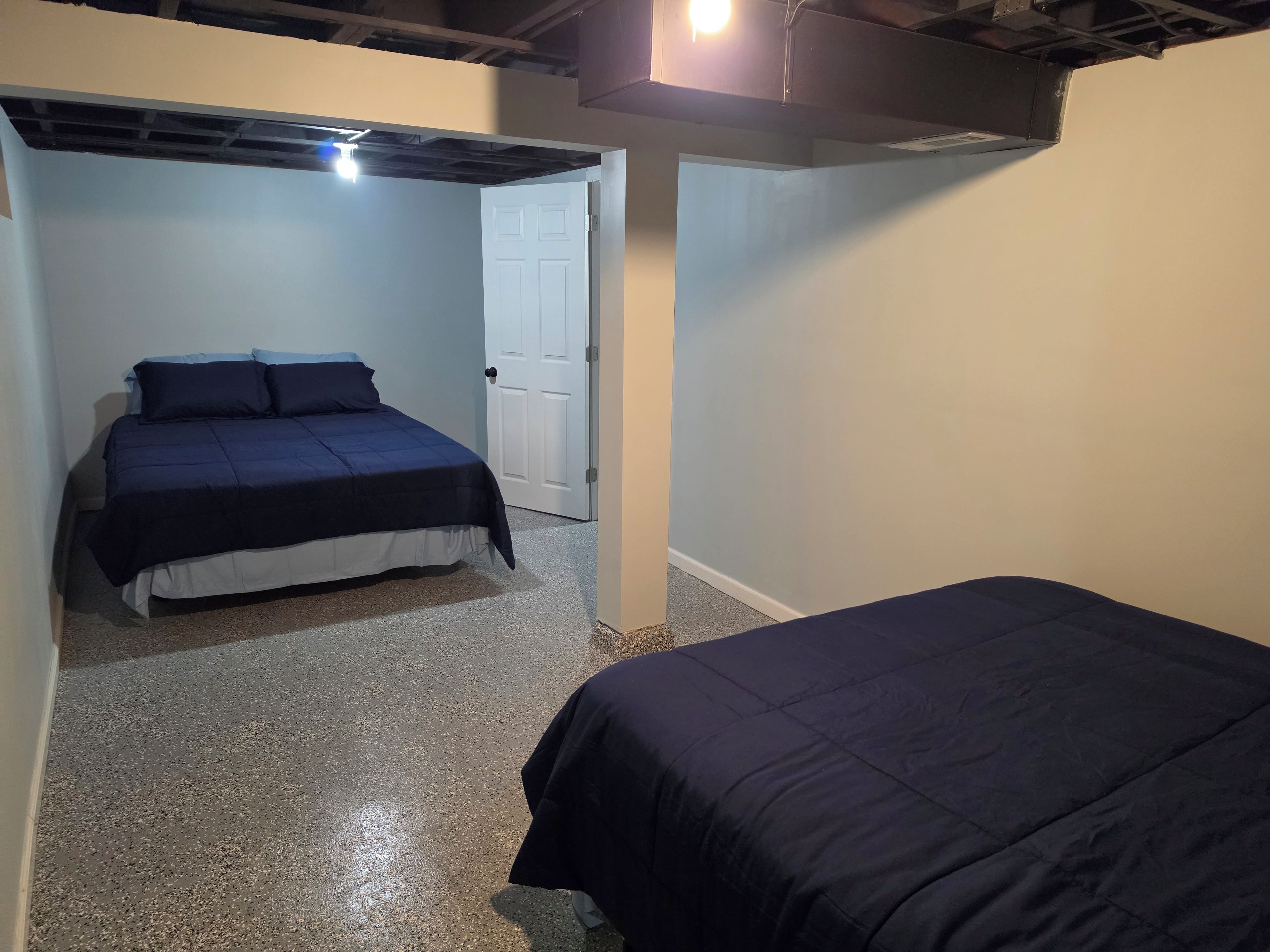 Une chambre à coucher avec un lit, une porte et un luminaire au plafond.