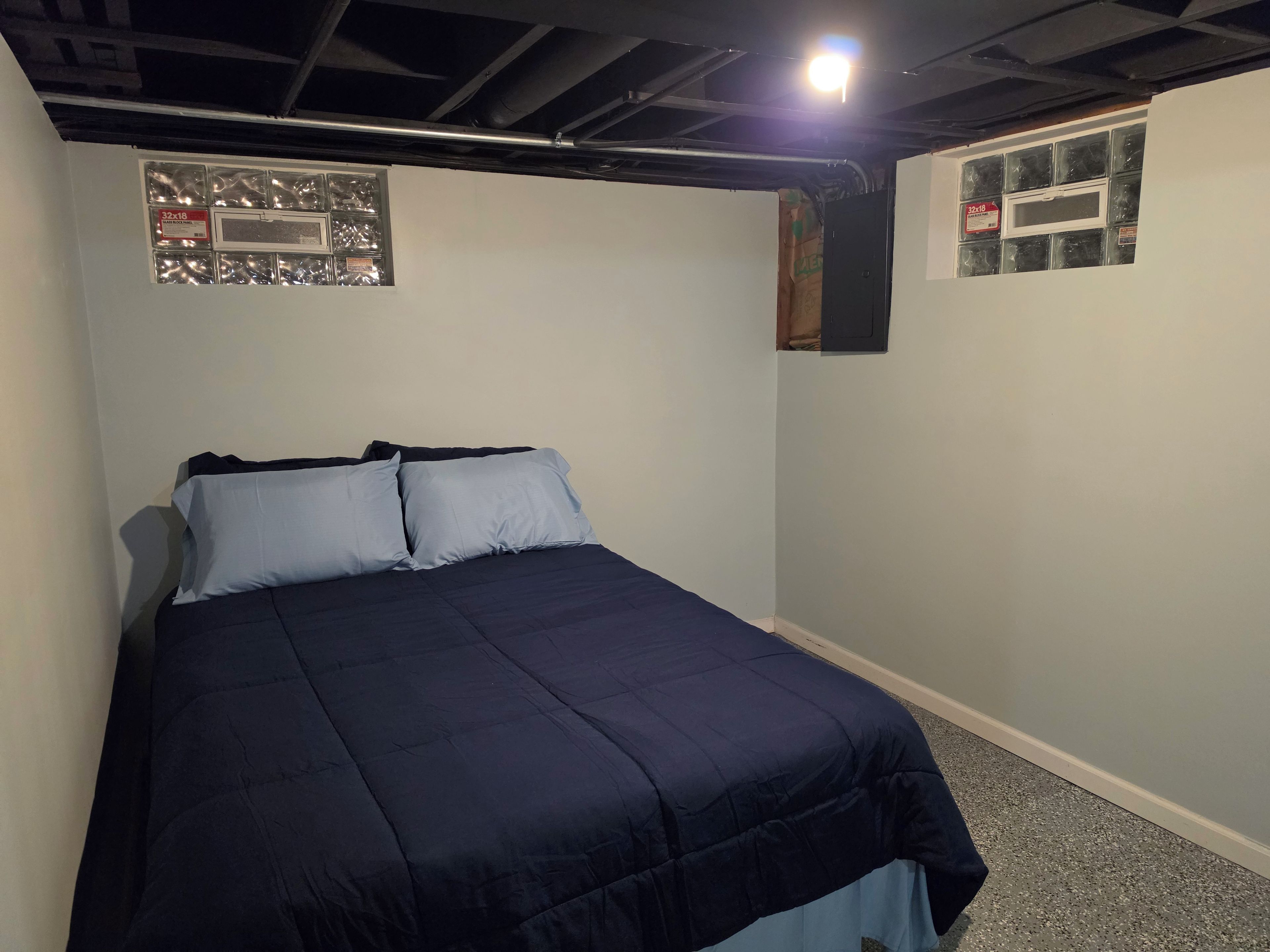 Una camera da letto con un letto, due cuscini, una finestra con persiane e un soffitto a vista con travi.