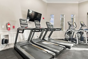 A gym with treadmills, a television mounted on the wall, and a fire extinguisher on the wall. - Vista Cay 2BR, Perfect for Parks and Conventions (Orlando)