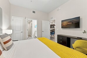 A hotel room with a bed, a desk, a chair, a television, and a painting on the wall. - Stay in Vista Cay, Amazing Location, Sleeps 8 (Orlando)