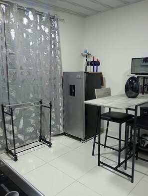 A kitchenette with a refrigerator, a table, and a chair. - New Listing (Cartago)