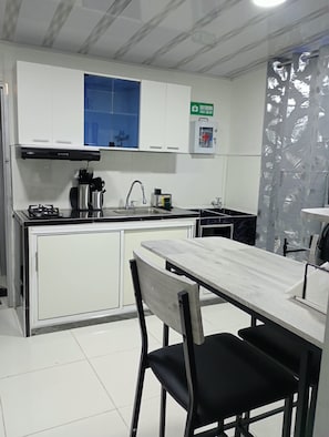 A kitchen with white cabinets, a blue window, a gas stove, and a sink. - New Listing (Cartago)