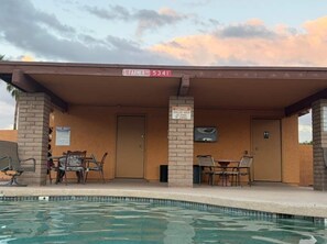 A covered pool area with lounge chairs, a sign indicating a caution for shallow water, and a street sign above. - Charming Oxford 2BR Pool & Vacation Stay (Tempe)