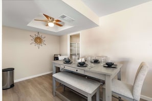 A dining area with a wooden table, bench, and ceiling fan. - Charming Oxford 2BR Pool & Vacation Stay (Tempe)
