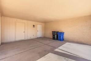 A garage with a concrete floor, two doors, and two trash bins. - Charming Oxford 2BR Pool & Vacation Stay (Tempe)