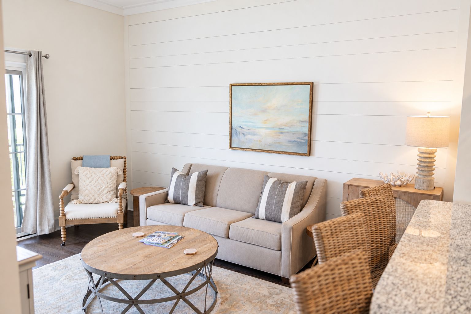 A living room with a sofa, armchair, round coffee table, and a painting on the wall.