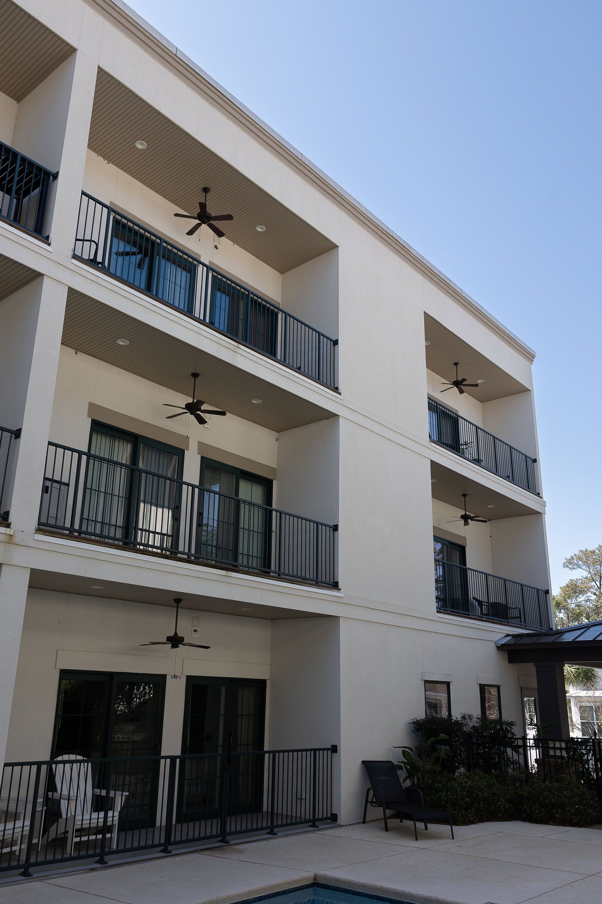 A multi-story residential building with balconies, a swimming pool, and outdoor seating.