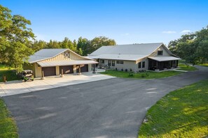A two-story building with a garage and a covered porch area. - Private 10-Acre Ranch Retreat — Sauna & Hot Tub (Morriston)